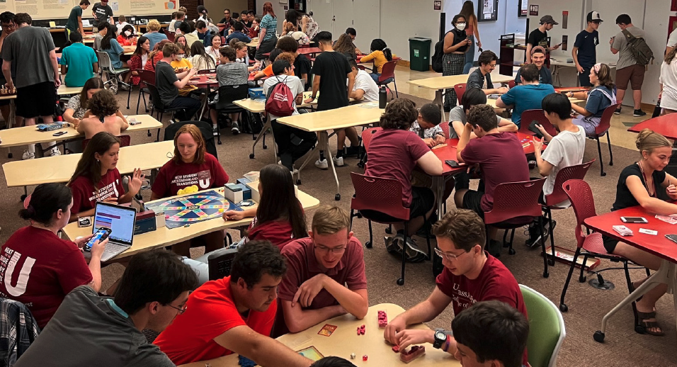 wide angle shot of many students playing board games in the libraries